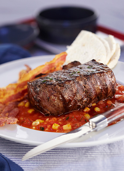 Bistec con salsa de tomate, maíz y tocineta