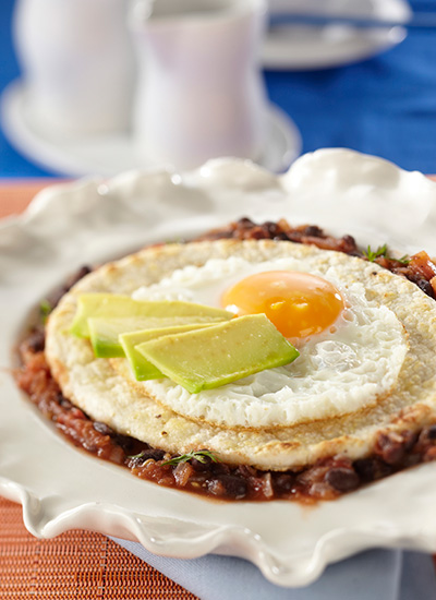 Huevo frito sobre arepa con salsa de tomate y fríjol negro