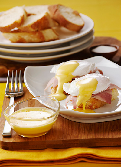 Huevos pochados sobre tostadas con jamón y salsa holandesa